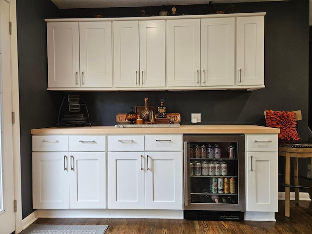 bar featuring stainless steel fridge, white cabinets, and dark wood-type flooring