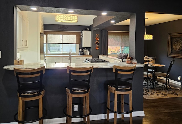 bar with white cabinetry, sink, light stone counters, and dark hardwood / wood-style flooring