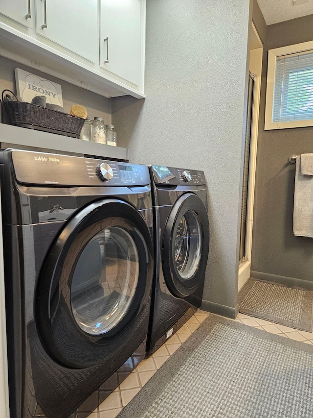 washroom with washing machine and dryer, cabinets, and light tile patterned floors