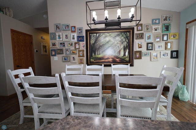 dining area with lofted ceiling, a notable chandelier, and hardwood / wood-style flooring