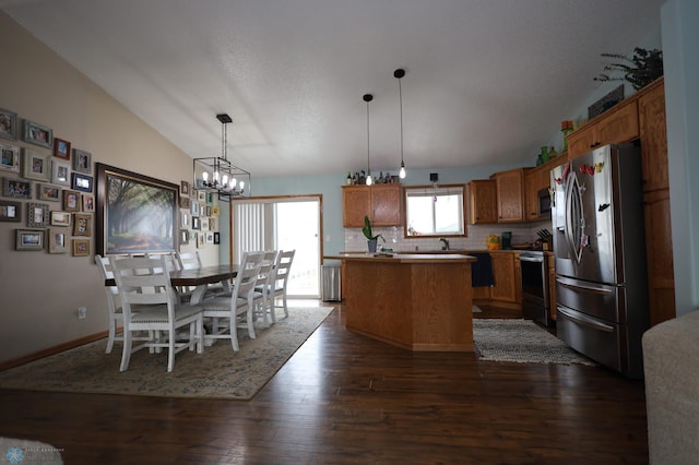 kitchen with a kitchen island, hanging light fixtures, stainless steel appliances, lofted ceiling, and dark wood-type flooring