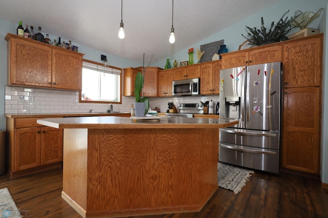 kitchen featuring stainless steel appliances, a center island, decorative light fixtures, and dark hardwood / wood-style flooring