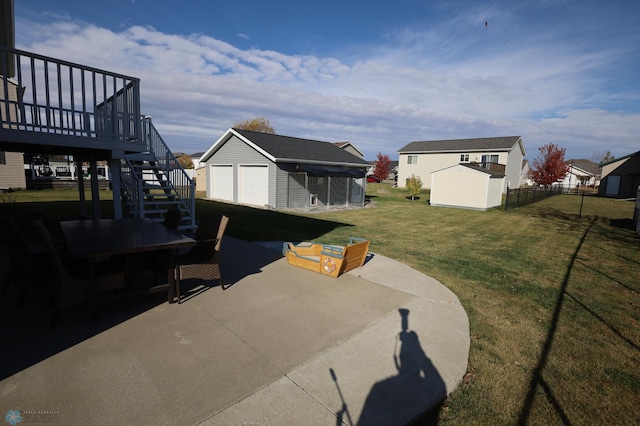 view of yard with a wooden deck, a patio area, an outbuilding, and a garage