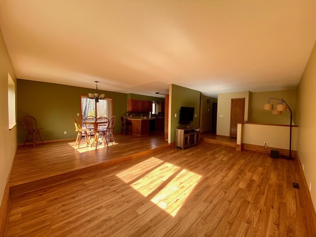 unfurnished living room with a notable chandelier and light hardwood / wood-style floors