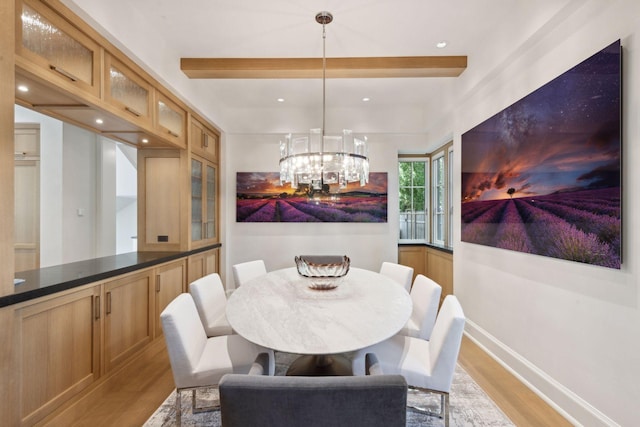 dining area with beamed ceiling, a chandelier, and light hardwood / wood-style floors