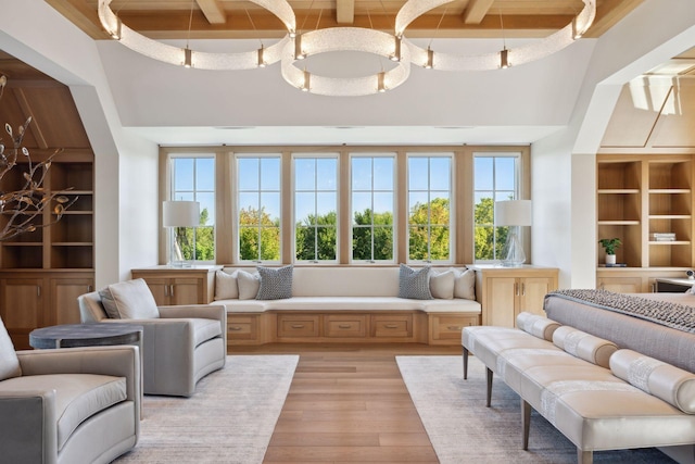 living area featuring beam ceiling, a healthy amount of sunlight, and light hardwood / wood-style flooring