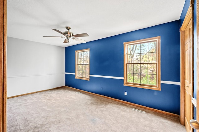 carpeted spare room with a textured ceiling, ceiling fan, and a wealth of natural light