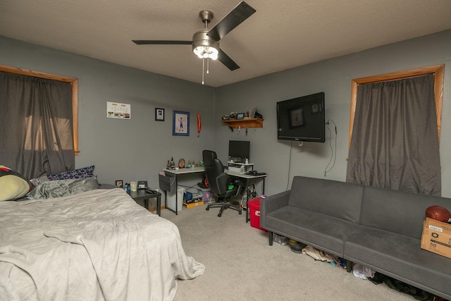 carpeted bedroom featuring ceiling fan and a textured ceiling