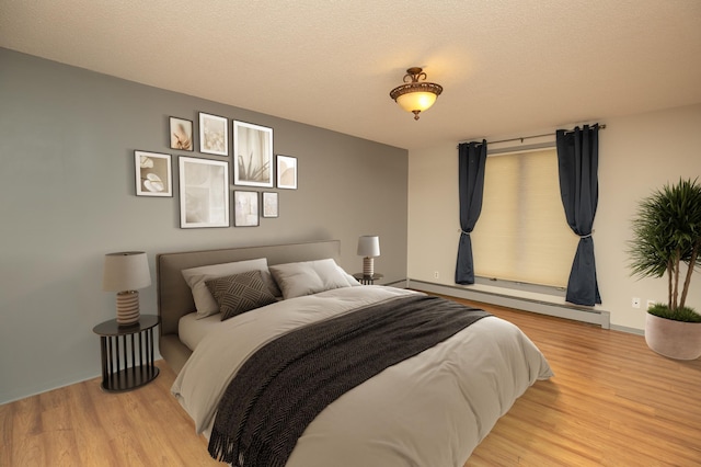 317 6th Ave SW Unit 501, Rochester, MN 55902 - bedroom featuring a baseboard heating unit, light wood finished floors, and a textured ceiling