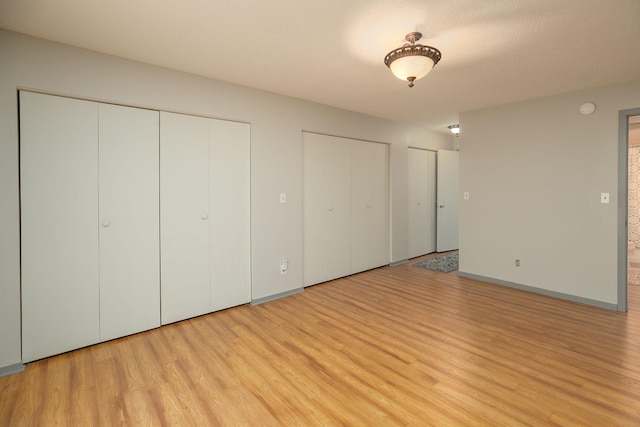 317 6th Ave SW Unit 501, Rochester, MN 55902 - unfurnished bedroom featuring two closets, light wood finished floors, and baseboards
