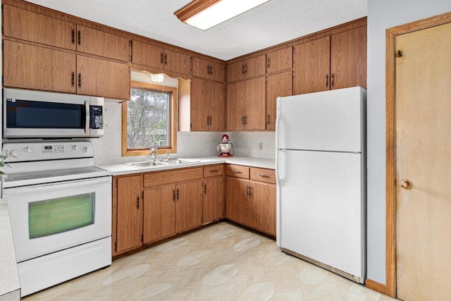 kitchen with brown cabinets, a sink, white appliances, tasteful backsplash, and light countertops