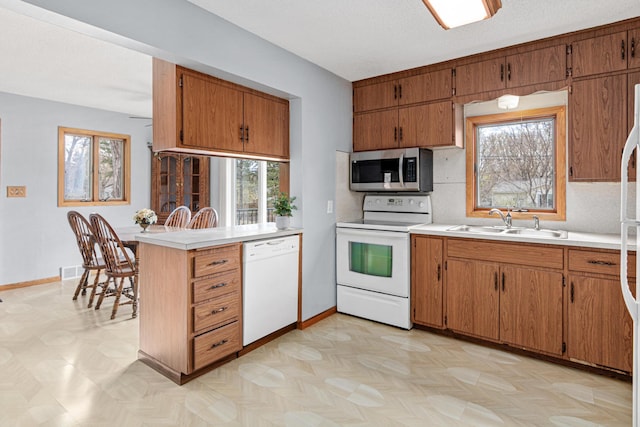 kitchen with light countertops, white appliances, plenty of natural light, and a sink