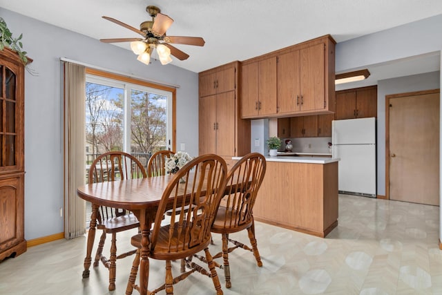 dining space with light floors, a ceiling fan, and baseboards