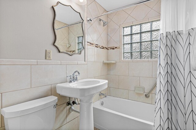 bathroom with shower / bath combo, toilet, and tile walls