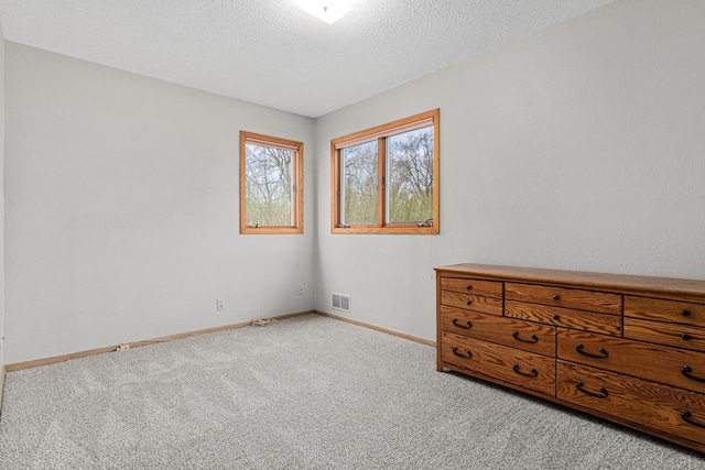 unfurnished bedroom with baseboards, visible vents, carpet floors, and a textured ceiling