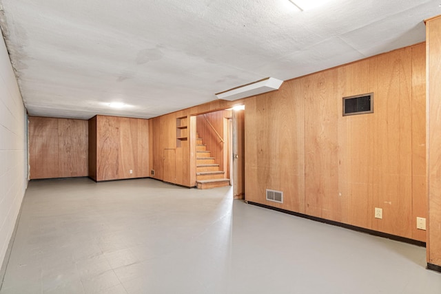 finished below grade area with visible vents, stairs, and wooden walls
