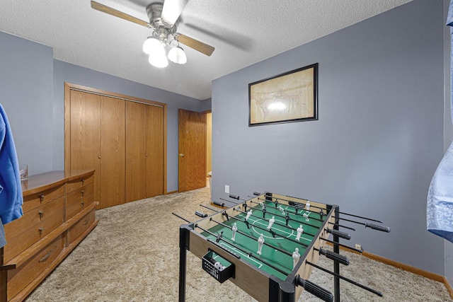 playroom featuring light carpet, a textured ceiling, and ceiling fan