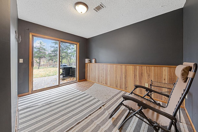 living area featuring a textured ceiling, wooden walls, and carpet floors