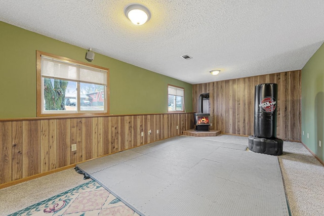 living room with a textured ceiling, a wood stove, and wood walls