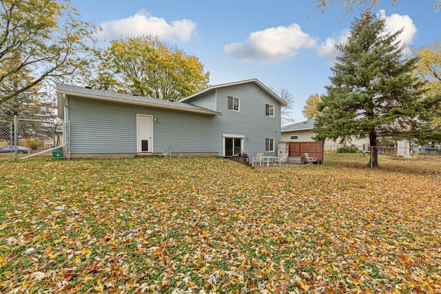 back of property with a deck and a lawn