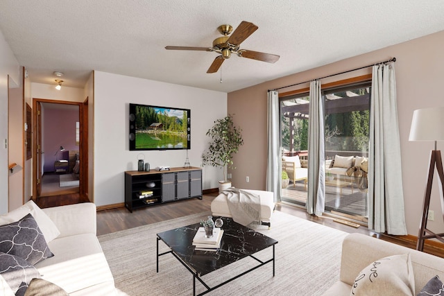 living room with a textured ceiling, light wood-type flooring, and ceiling fan