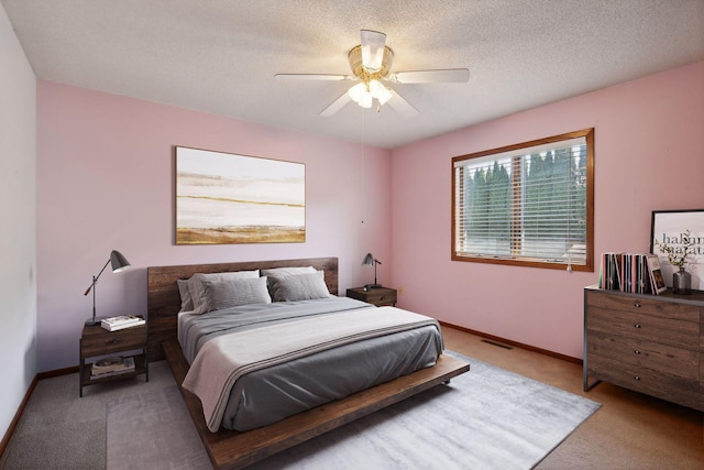 carpeted bedroom with ceiling fan and a textured ceiling