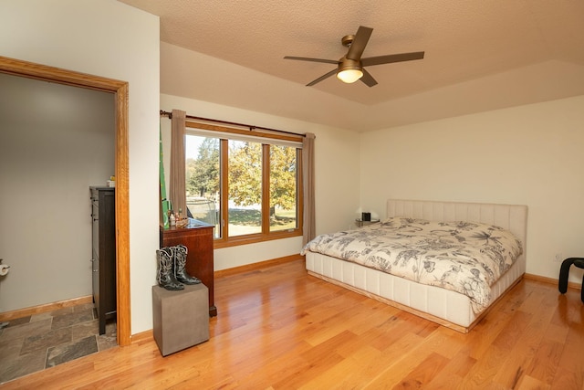 bedroom with a textured ceiling, wood-type flooring, and ceiling fan