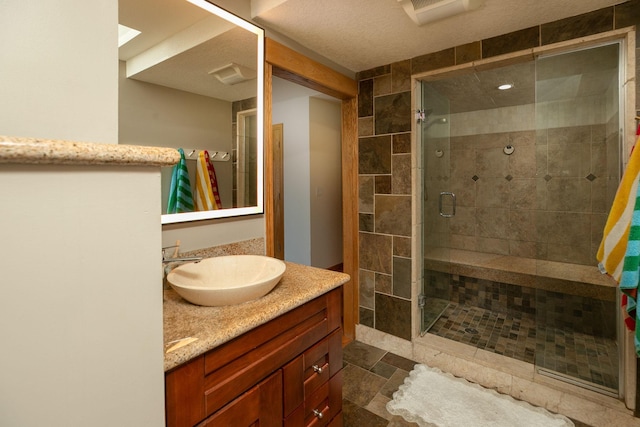 bathroom with vanity, a textured ceiling, a skylight, and a shower with door