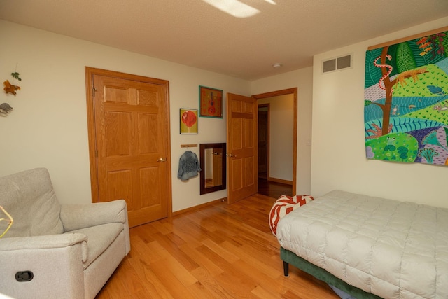 bedroom with light hardwood / wood-style floors and a textured ceiling