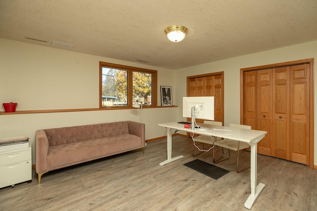 office area with light hardwood / wood-style floors and a textured ceiling