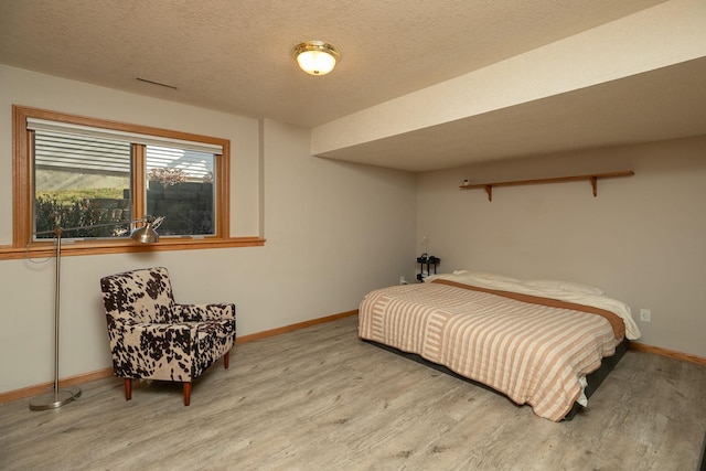 bedroom with a textured ceiling and light wood-type flooring