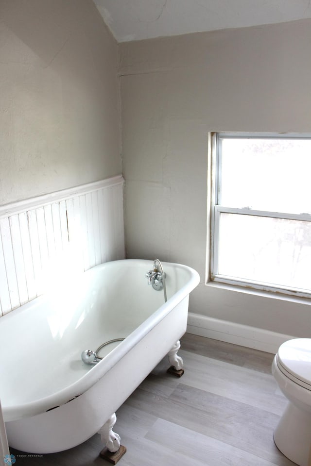 bathroom featuring a bathtub, toilet, and hardwood / wood-style flooring