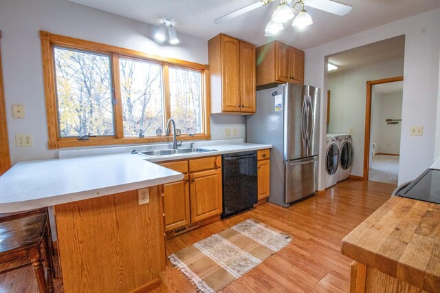 kitchen with stainless steel fridge, black dishwasher, light wood-type flooring, independent washer and dryer, and sink