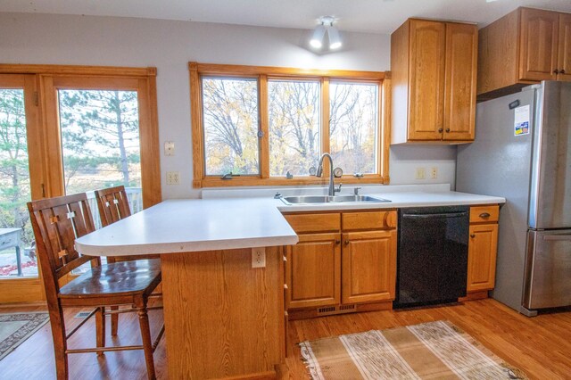 kitchen with dishwasher, a breakfast bar area, stainless steel fridge, sink, and light wood-type flooring