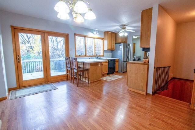 kitchen featuring stainless steel refrigerator, light hardwood / wood-style flooring, dishwasher, ceiling fan with notable chandelier, and sink