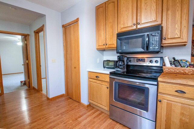 kitchen featuring stainless steel range with electric stovetop, wood counters, and light wood-type flooring