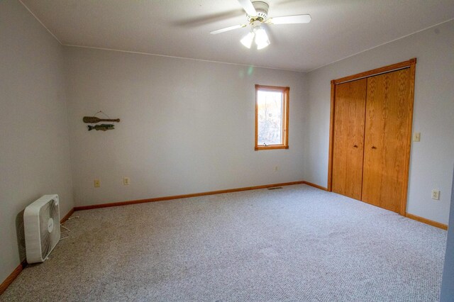 unfurnished bedroom with a closet, light colored carpet, and ceiling fan