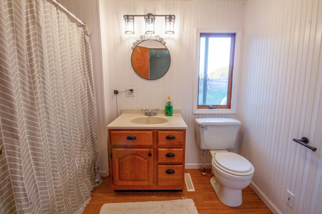 bathroom with toilet, walk in shower, vanity, and wood-type flooring