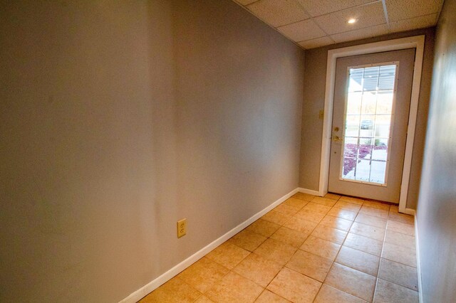 doorway featuring a drop ceiling and light tile patterned floors