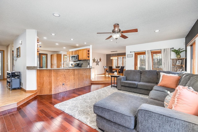 living room featuring ceiling fan, a textured ceiling, and dark hardwood / wood-style flooring