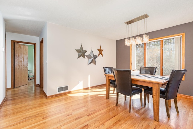 dining room featuring a notable chandelier, a textured ceiling, and light wood-type flooring