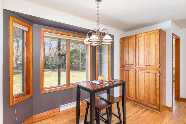 dining space featuring light hardwood / wood-style flooring, a notable chandelier, and a textured ceiling