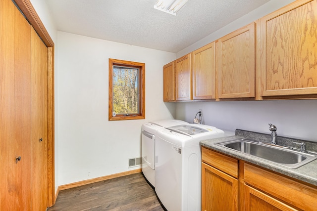 washroom with cabinets, washer and dryer, a textured ceiling, dark wood-type flooring, and sink