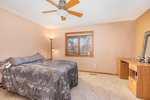 carpeted bedroom with ceiling fan and a textured ceiling