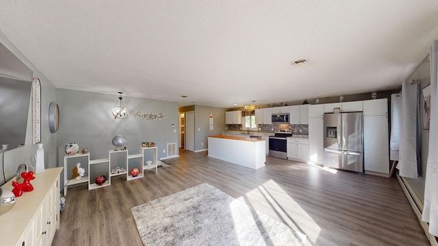 kitchen with a kitchen island, backsplash, stainless steel appliances, white cabinets, and hardwood / wood-style flooring