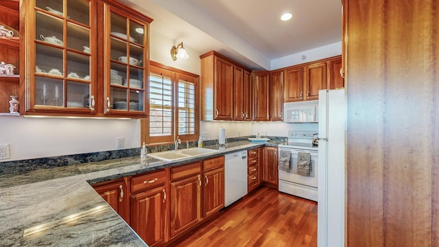 kitchen featuring white appliances, dark stone countertops, sink, and dark hardwood / wood-style floors