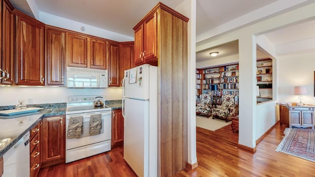 kitchen with dark stone countertops, dark wood-type flooring, and white appliances