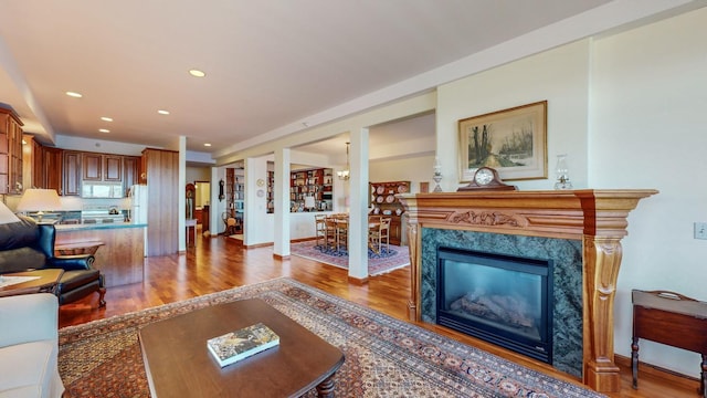 living room with a high end fireplace, a chandelier, and wood-type flooring