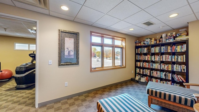 living area with light carpet and a drop ceiling