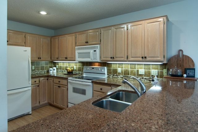 kitchen featuring white appliances, backsplash, dark stone countertops, sink, and light hardwood / wood-style floors